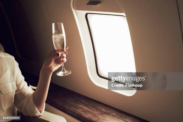 businesswoman relaxing aboard private jet - wijn drinken stockfoto's en -beelden