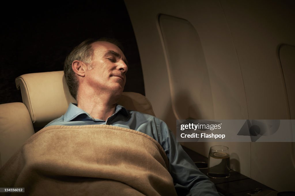 Businessman sleeping aboard private jet
