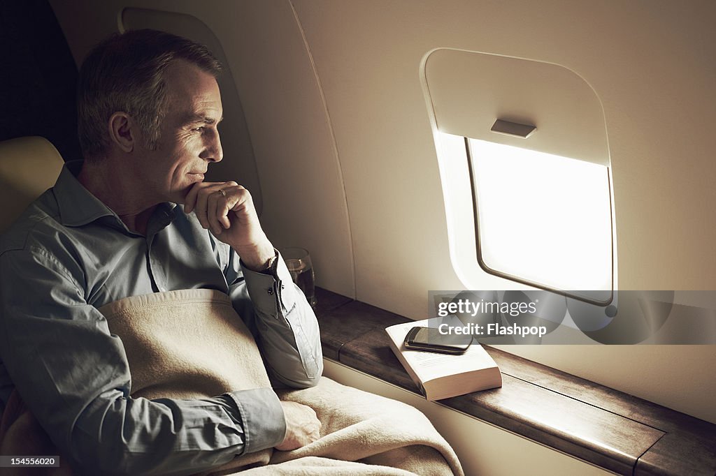 Businessman gazing out of window aboard flight