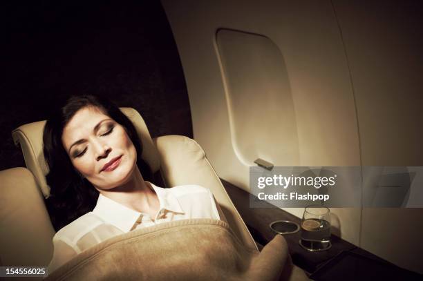 businesswoman relaxing aboard private jet - business class reclining plane stock pictures, royalty-free photos & images