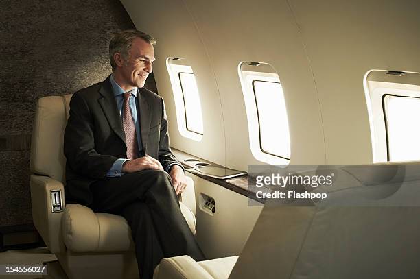 business man travelling aboard a private jet - millionnaire stock pictures, royalty-free photos & images