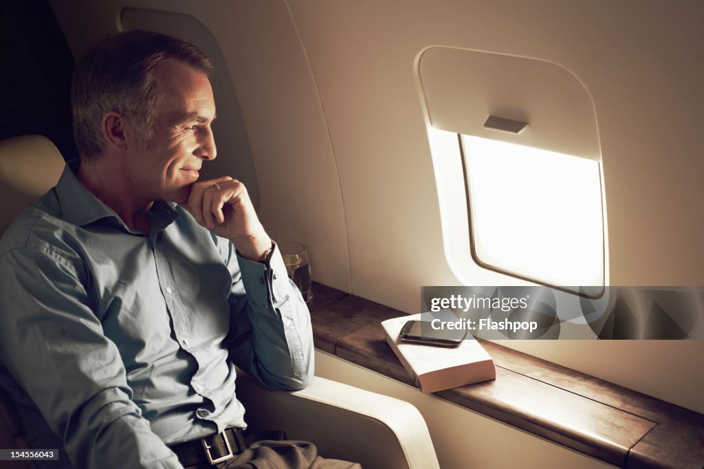 Businessman gazing out of window aboard flight