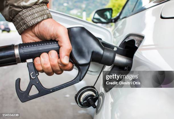 mans's hand holding fuel nozzle in car - gas pump stockfoto's en -beelden