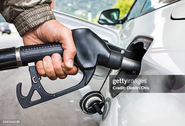 mans's hand holding fuel nozzle in car - refueling 個照片及圖片檔