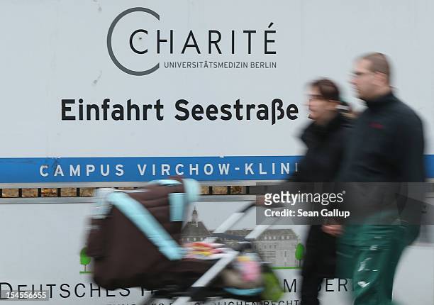 Couple pushing a baby in a stroller walk past a sign marking an entrance to the Virchow campus of Charite hospital two days after Charite officials...