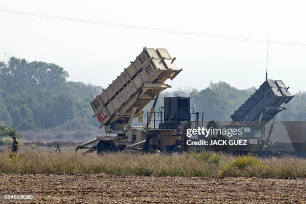 An Israli soldier walks nearby two patriot missile batteries, deployed on a field close to Atlit, on the outskirts of Haifa, on October 22, 2012....