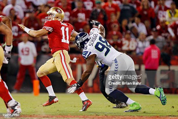 Quarterback Alex Smith of the San Francisco 49ers rolls out of the pocket to make an incomplete pass under pressure from defensive end Greg Scruggs...