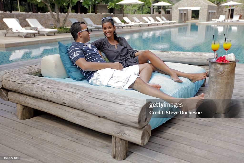 Happy couple drinking cocktail near the pool