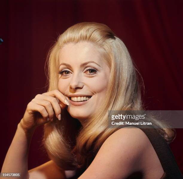 Plan smiling face of Catherine Deneuve in brown sleeveless dress, one hand on the cheek during a break in the filming of 'Beautiful Day' by Luis...