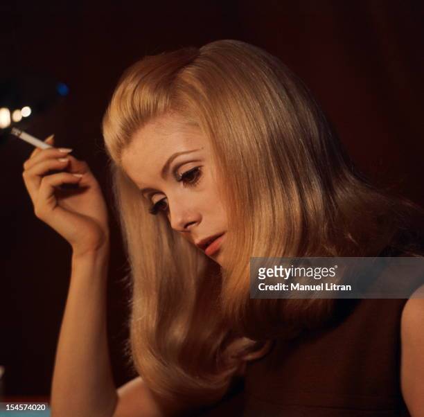 Plan three-quarters of Catherine Deneuve in brown sleeveless dress, head tilted, a cigarette in his hand during a break in the filming of 'Beautiful...