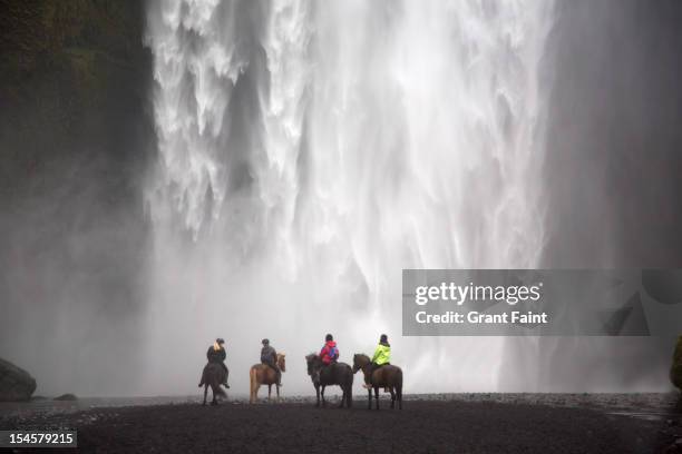 tourists on ponies before waterfalls. - iceland horse stock pictures, royalty-free photos & images