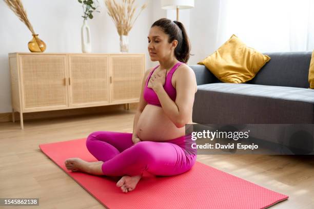 side view of a pregnant woman meditating while doing yoga at hom - hom stock pictures, royalty-free photos & images