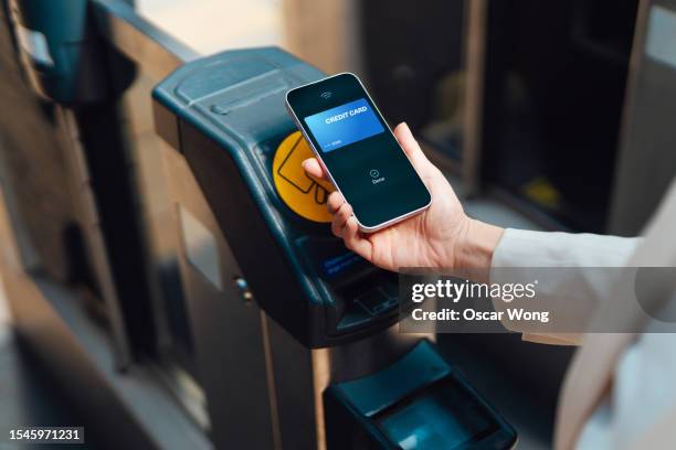 commuter making contactless payment with smartphone at the gate in train station - paid palabra en inglés fotografías e imágenes de stock