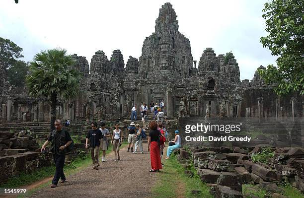Visitors walk the ruins of Bayon in the center of Angkor Thom May 27, 2002 in Angkor, Cambodia. Built as a Buddhist temple around 1300 A.D., just...