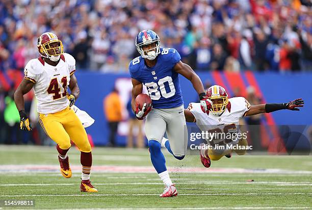 Victor Cruz of the New York Giants runs in a touchdown reception late in the fourth quarter against Madieu Williams and Josh Wilson of the Washington...