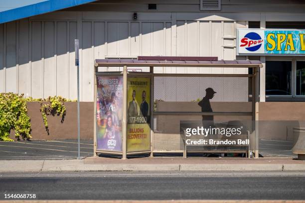 Person waits in the shade under a bus stop during a heat wave on July 15, 2023 in Phoenix, Arizona. Weather forecasts today are expecting...