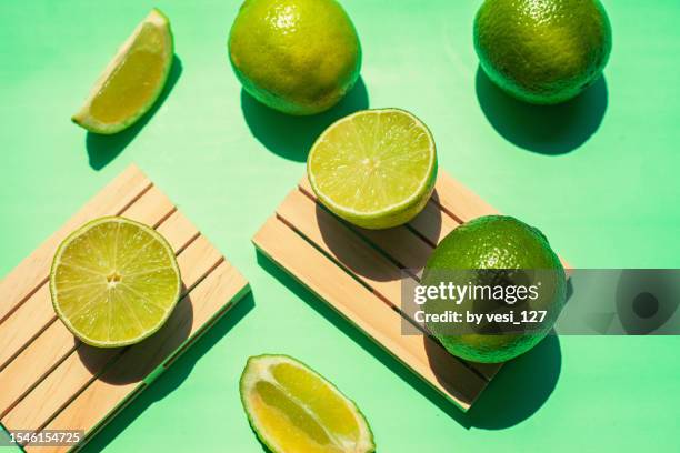 flat lay - limes on green background - key lime stock pictures, royalty-free photos & images