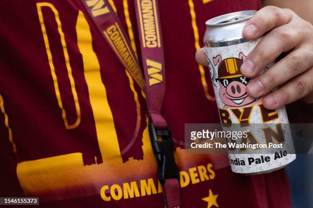 Washington Commanders fans drinks a commemorative beer after NFL team owners unanimously approved Josh Harris's purchase of the team from Daniel...