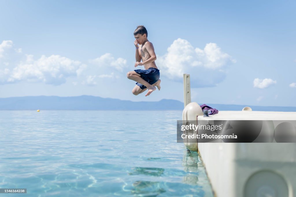 Boy jumping in sea water at summer holiday