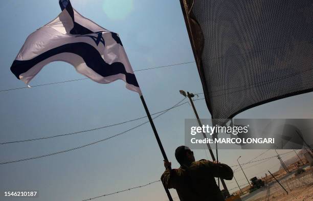 An Israeli soldier leans on a pole supporting the national flag at the main check point to the West Bank town of Jericho where a meeting is scheduled...