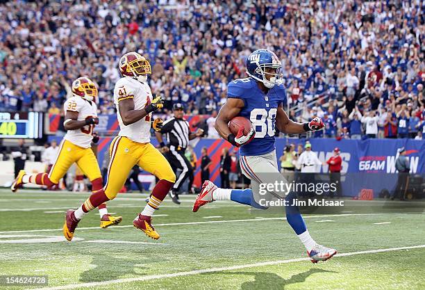 Victor Cruz of the New York Giants runs in a touchdown reception late in the fourth quarter against Madieu Williams of the Washington Redskins at...