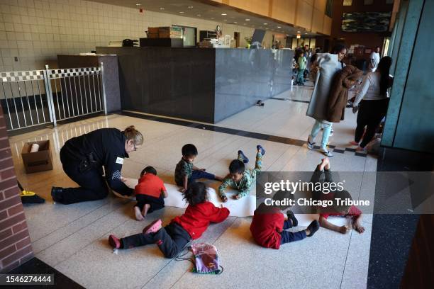 Chicago police officer briefly draws with a child after setting up a large piece of paper as Venezuelan migrant families take shelter in the lobby of...