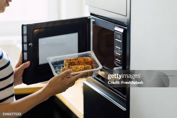 anonyme frau, die eine mahlzeit in einem mikrowellenherd zubereitet - ready meal stock-fotos und bilder