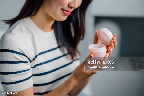 unrecognizable woman applying face cream - applying stockfoto's en -beelden