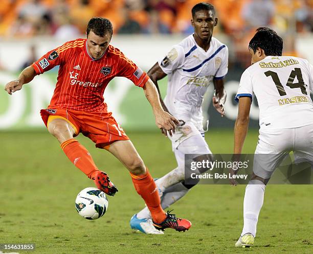 Cam Weaver of the Houston Dynamo looks for room to maneuver as Israel Fonseca of the Olimpia defends at BBVA Compass Stadium on October 23, 2012 in...
