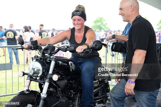 Festival goers ride a stationary motorcycle at Harley-Davidson and Livewire JUMPSTART during Harley-Davidson's Homecoming Festival - Day 2 at...