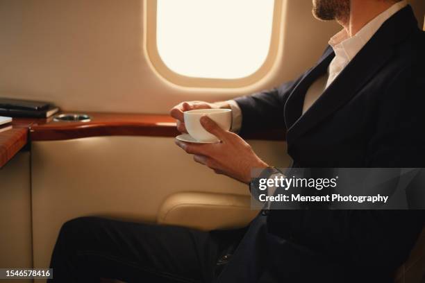 unrecognizable elegant ceo businessman traveler drinks coffee while in flight in the first-class private airplane jet - airliners stock pictures, royalty-free photos & images