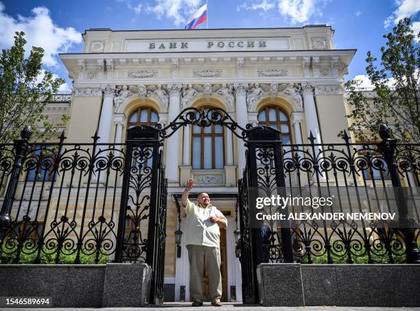 Man waves to a taxi leaving the Russian Central Bank headquarters in downtown Moscow on July 21, 2023. The Russian Central Bank on July 21, 2023...