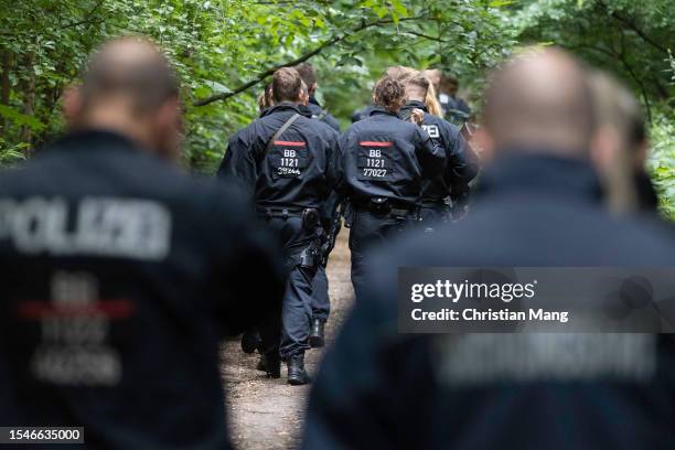 Police officers walk in a forest during the second day of efforts to capture what authorities believe to be an escaped lioness near Berlin on July...