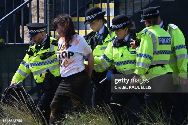 Police officers escort a protestor from Just Stop Oil away from the 17th green on day two of the 151st British Open Golf Championship at Royal...