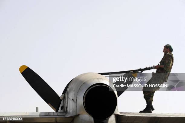 An Afghan National Army soldier hauls a fuel line across an aircraft wing at Kabul military airport on June 17 as troops prepare to emplane for...