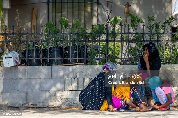 Family sits in the shade while waiting for a ride during a heat wave on July 15, 2023 in Phoenix, Arizona. Weather forecasts today are expecting...