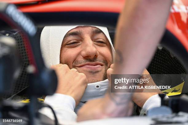 Alpha Tauri's Australian driver Daniel Ricciardo adjust his balaclava as he prepares for the first practice session at the Hungaroring race track in...