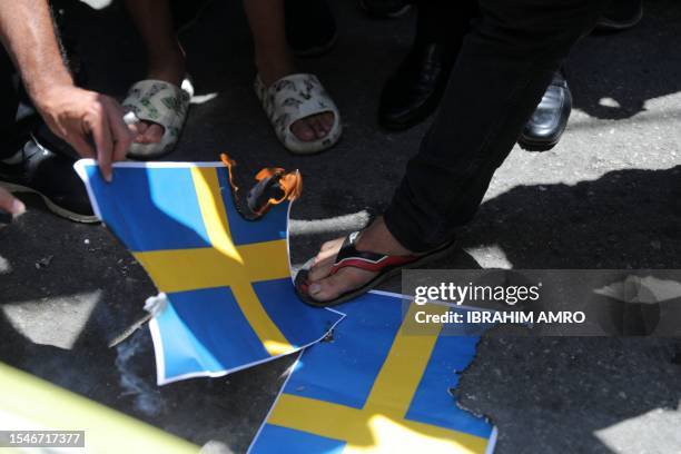 People step on Swedish flags as they participate in a demonstration called for by the Lebanese Shiite Hezbollah movement, to denounce the burning of...