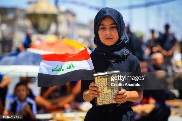 Child holds Quran and flag of Iraq as the followers of Shia cleric Muqtada al-Sadr protest against the act of Quran burning, in Baghdad, Iraq on July...