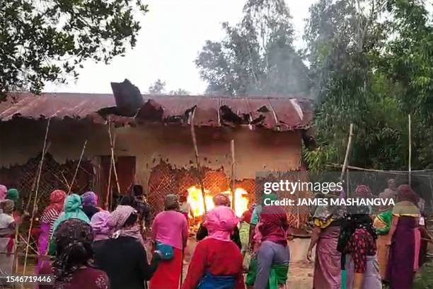 This screen grab made from AFPTV video footage taken on July 20 shows women burning the house of one of the men accused of parading two women naked...