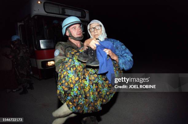 Soldier soldier carries a wounded elderly woman upon her arrival to the frontline crossing point close to the government held town of Klandanj on...