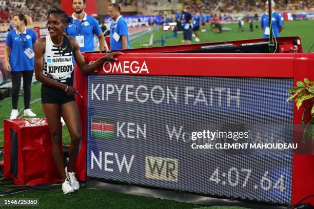 Faith Kipyegon of Kenya poses next to the score board after breaking the World Record and winning in the Women's One Mile event during the IAAF...
