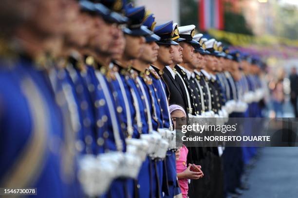 Young girl watches a ceremony commemorating the first anniversary of Paraguayan President Fernando Lugo's administration in office from in between a...