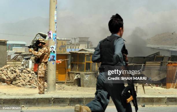 Soldier serving with the NATO-led International Security Assistance Force aims his weapon as a member of the Afghan National Police secures the site...