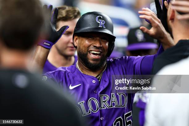 Elias Diaz of the Colorado Rockies high fives teammates in the dugout after hitting a home run during the third inning of a game against the Miami...