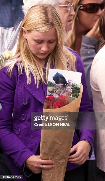 Mourner holds a bunch of flowers with a picture of Rifleman Daniel Simpson of 2 Rifles as a procession of hearses carrying the bodies of eight...