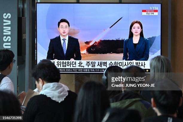 People watch a television screen showing a news broadcast with file footage of a North Korean missile test, at a railway station in Seoul on July 22,...