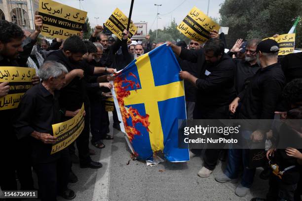 Iranian worshippers burn a Sweden flag during a protest against Koran burning in the Swedish capital Stockholm, at the Imam Khomeini Grand Mosque...
