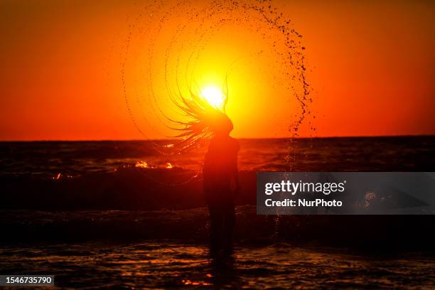 Palestinian girl swim in Gaza beach on a hot weather and enjoy during the sunset, Friday, July 21, 2023.