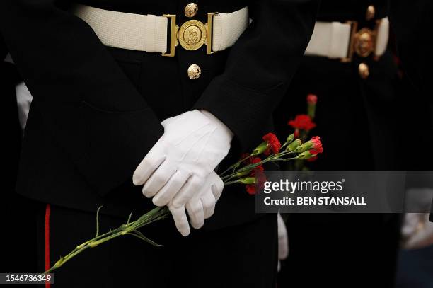 Mourners hold flowers as a convoy of hearses containing the bodies of seven British soldiers killed in Afghanistan, passes through the village of...